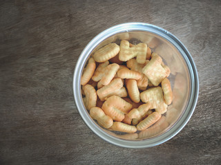 Top view letter biscuit in yellow cup on wooden background