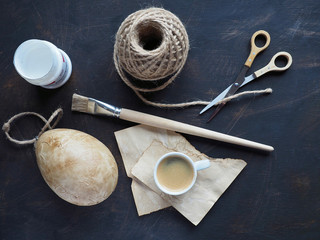 Easter egg decorated by decoupage technique. Decoupage tools - handmade paper colored by coffee, brush, cord, glue and scissors.