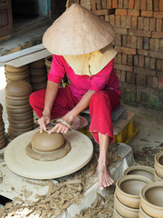 A local Vietnam woman manufacturing bowls on pottery wheal. Than Ha pottery village. Vietnam, March 2017.