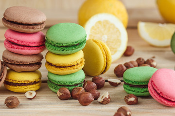 Green, pink, yellow and brown french macarons with lemon, kiwi and hazelnuts