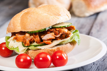 Fried chicken meat with cheese and vegetables in bun