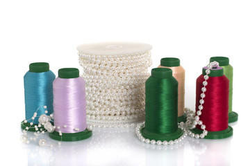 Colored silk threads, pearls. Goods for needlework on a white background.