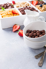Variety of cold quick breakfast cereals with berries in white wooden box, healthy eating for kids, selective focus, copy space.