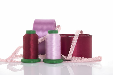 Threads for embroidery, satin ribbons, sewing thread and needlework on a white background