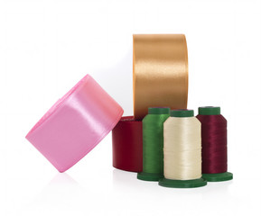 Satin ribbons and threads on bobbins for needlework on a white background