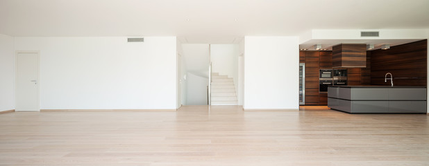 Empty white room with brown kitchen