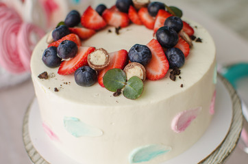 Delicious cream cake with chocolate balls decorated with strawberries and blueberries