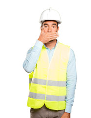 Surprised engineer covering his mouth with his hand against white background