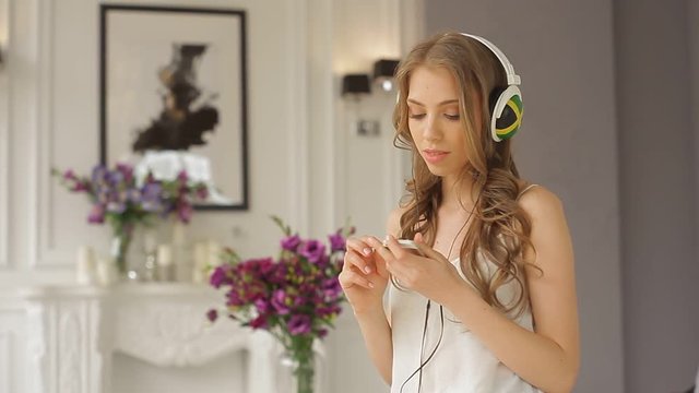 Happy girl is dancing in headphones in her luxurious apartment