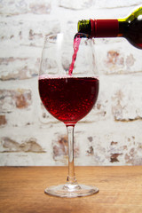 Glass of full bodied red wine being poured