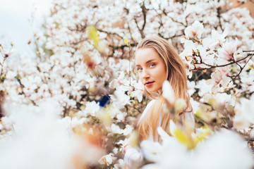 Beauty woman around magnolia pink flowers tree in spring garden