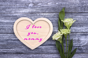 Fototapeta na wymiar Decorative white wooden heart on grey wooden background with lettering Happy Mother's Day.