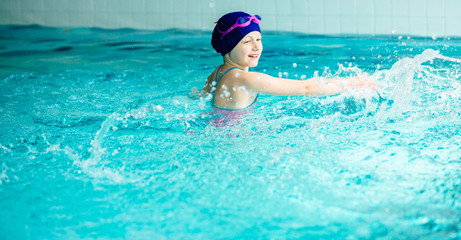 Little girl splashing water in swimming pool