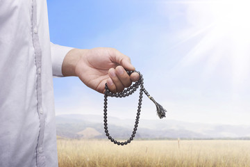 Hand of muslim man praying while holding tasbih