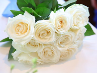 White roses bouquet with blue ribbon on a old white table
