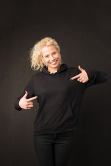 Woman in black hoodie pointing with both hands at it