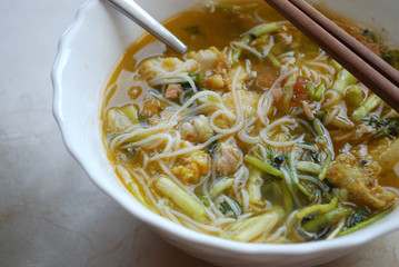 Bowl of rice noodle soup with a pair of chopsticks.