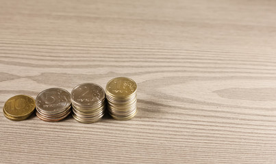 stacks of coins in shape of ladder on a wooden surface