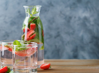 Detox water with fresh mint and strawberries in transparent glasses against the blue wall