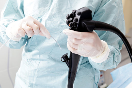 Lekarz trzyma głowicę operacyjną kolonoskopu.  
