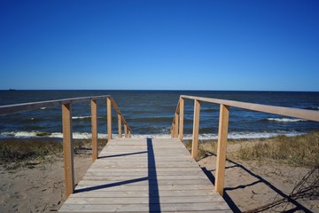 beach sea water pier sky ocean blue sand walkway sun