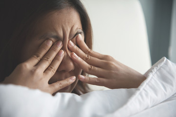 Asian woman rubbing eyes with her hands on her bed. Copy space. - obrazy, fototapety, plakaty