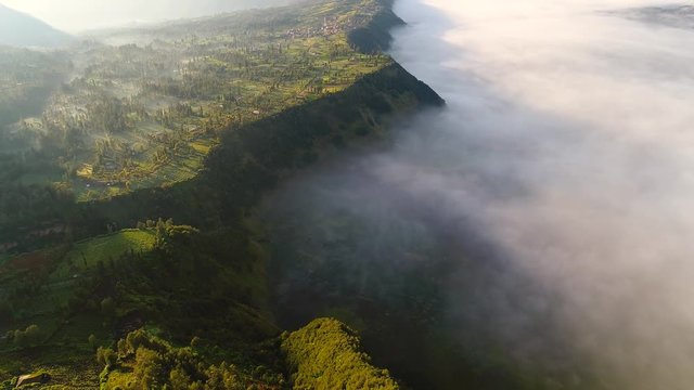 Aerial view flight over Cemoro Lawang, small village in morning mist. Which situated on the edge of massive north-east of Mount Bromo, East Java, Indonesia
