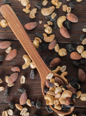 Spoon with nuts and raisins on a wooden background. Top view.