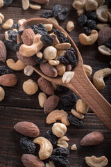 Spoon full of nuts and raisins on a wooden background.