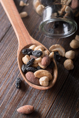Spoon with jar full of nuts and raisins on a wooden background. Top view.