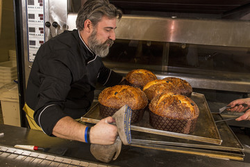 Cocinero horneando panetones en horno industrial.