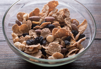 Oat flakes in bowl with mix nuts and dry fruits on wooden background