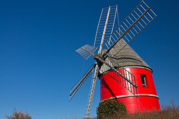beautiful wind red mill rising up in blue sky, nailloux, france