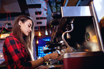 Fototapeta na wymiar Bartender girl is making coffee in a bar.