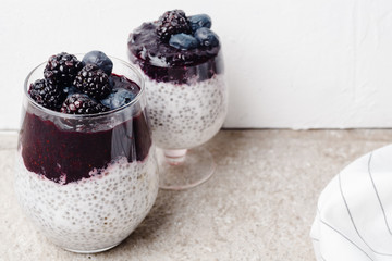 Healthy chia pudding with coconut milk, blackberry and blueberry smoothie on concrete white background. Superfood concept. Copy space