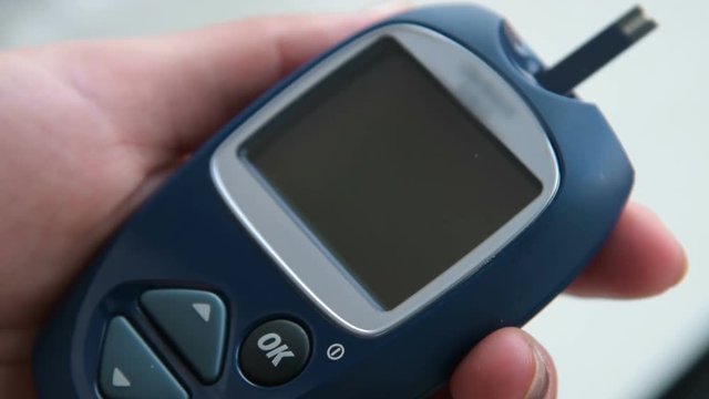 Close-up shot of inserting blood test strip into the glucometer. It is ready to measure sugar level