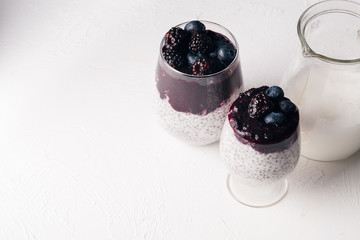 Healthy chia pudding with coconut milk, blackberry and blueberry smoothie on concrete white background. Superfood concept. Copy space