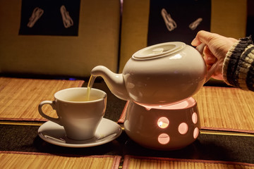 Female hand pours tea in cup