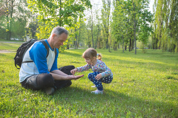 Father with a little daughter are playing in the park