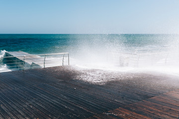 Waves crash against the promenade