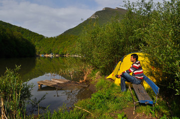 Young man camping by the river and get rest in nature.  Morning on the river
