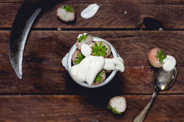 Ananaserdbeeren auf rustikalem Holztisch mit Löffel und Joghurt