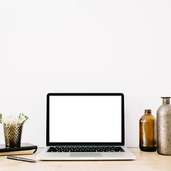 Blogger or freelancer workspace with front view of laptop with blank screen at white background. Minimalistic decorated home office desk.