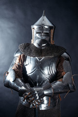 A medieval warrior in a helmet and with a sword. Knight on dark background