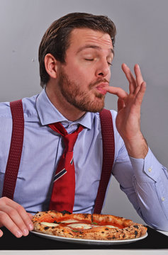 Hombre de negocios comiendo y disfrutando una pizza.