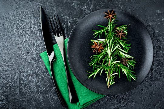 Christmas tree of rosemary and anise on a black plate background. Selective focus.Top view. Place for text.