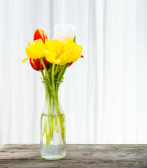 gula och röda tulpaner i en glas vas 