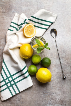 Vaso de Limonada junto a limones, una cuchara y una servilleta sobre una tabla gris. Vista superior