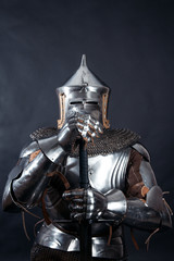 A medieval warrior in a helmet and with a sword. Knight on dark background