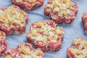 raw fresh pork cutlets with fried onions in the shape of a flower on parchment paper